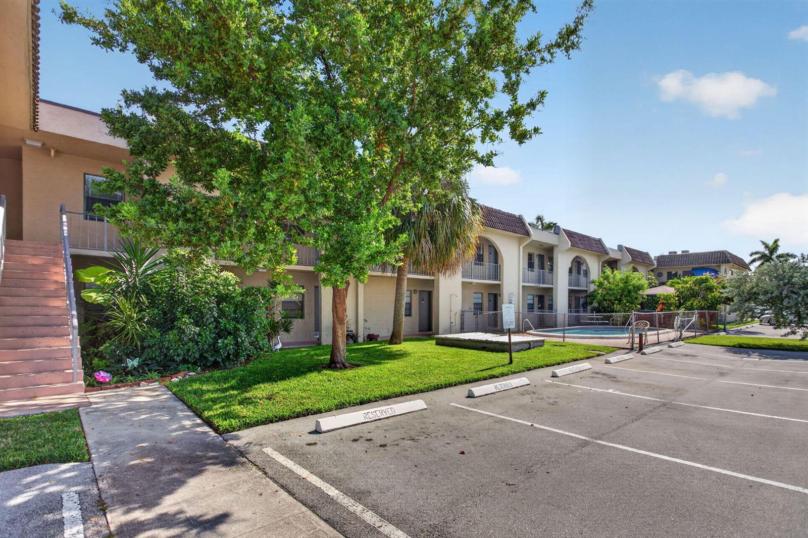 An exterior view of a multi-story apartment building with a parking lot and swimming pool — 2141 NE 42nd Street # 204, Lighthouse Point FL 33064, LIGHTHOUSE POINT, FL