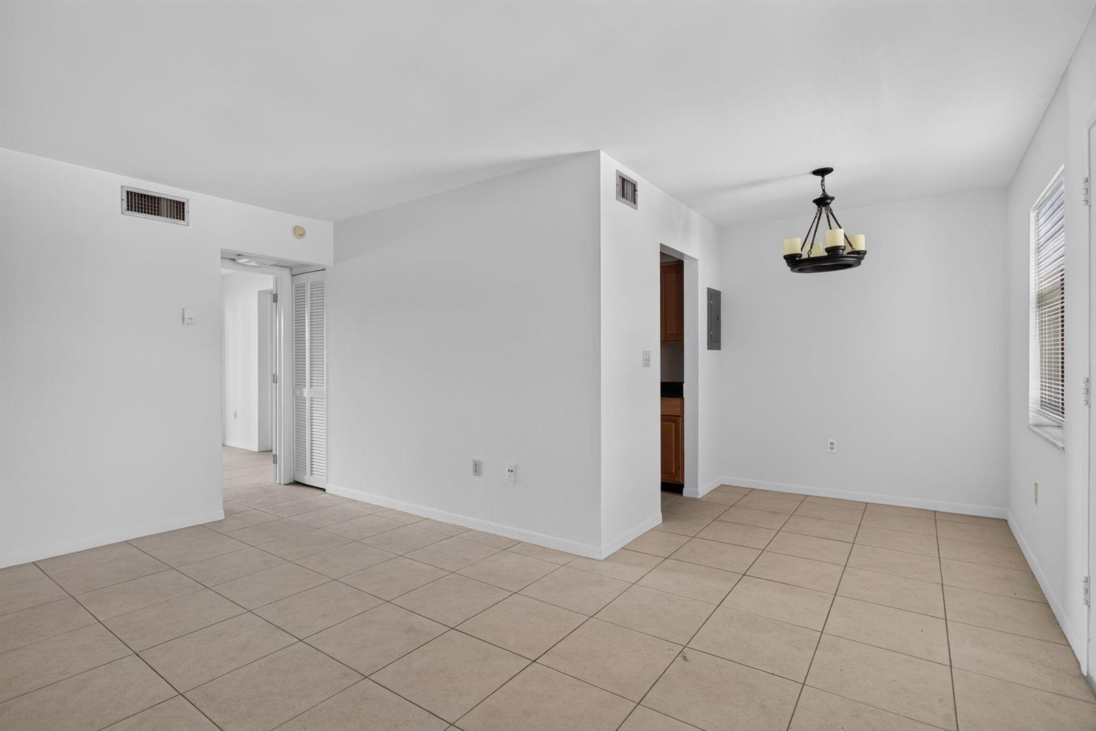 An empty room with beige tile flooring, white walls, and a hanging chandelier — 2141 NE 42nd Street # 204, Lighthouse Point FL 33064, LIGHTHOUSE POINT, FL