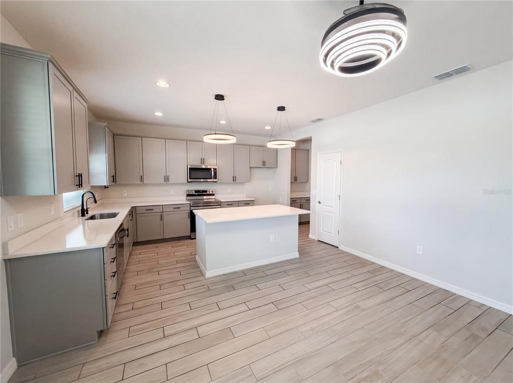 A kitchen features gray cabinets, white countertops, a center island, and wood-look tile flooring — 4510 PENKERT PLACE, LAKELAND, FL