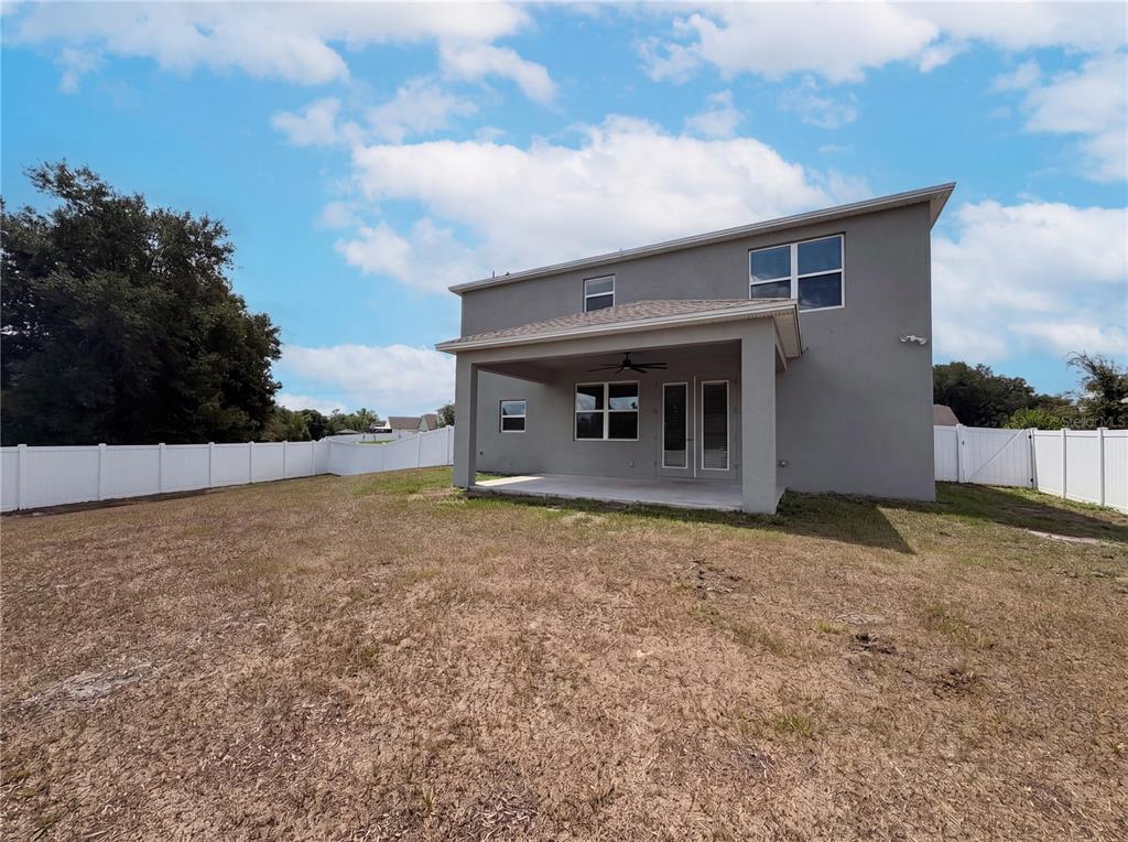 The exterior rear view of a two-story gray house with a covered patio and fence — 4510 PENKERT PLACE, LAKELAND, FL