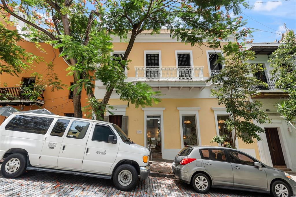 A yellow two-story building with a balcony sits on a cobblestone street with parked cars — 70 CALETA DE SAN JUAN UNIT 2, OLD SAN JUAN, PR
