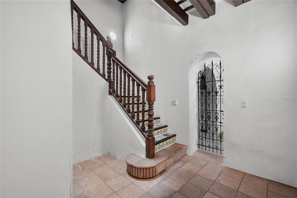 A staircase with decorative tile risers and a wooden railing stands beside an arched gate — 70 CALETA DE SAN JUAN UNIT 2, OLD SAN JUAN, PR