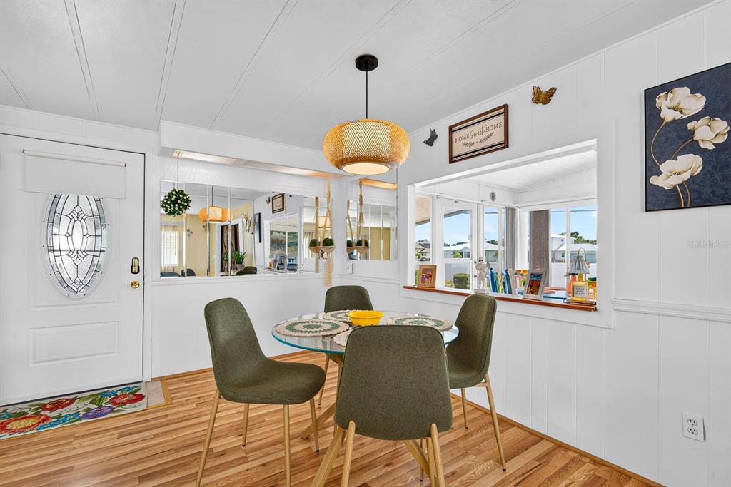 A dining area features a glass table, four green chairs, and a large wall mirror — 2107 PALMA SOLA BOULEVARD UNIT 17, BRADENTON, FL