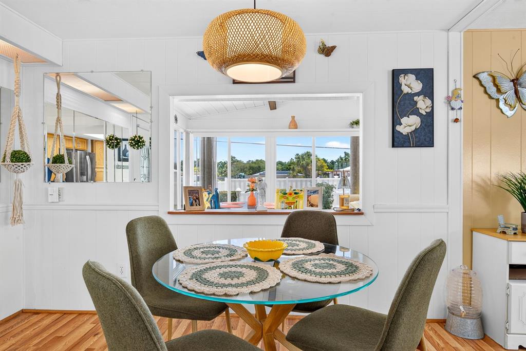 A dining area features a glass-topped table, four olive chairs, and a woven pendant light — 2107 PALMA SOLA BOULEVARD UNIT 17, BRADENTON, FL