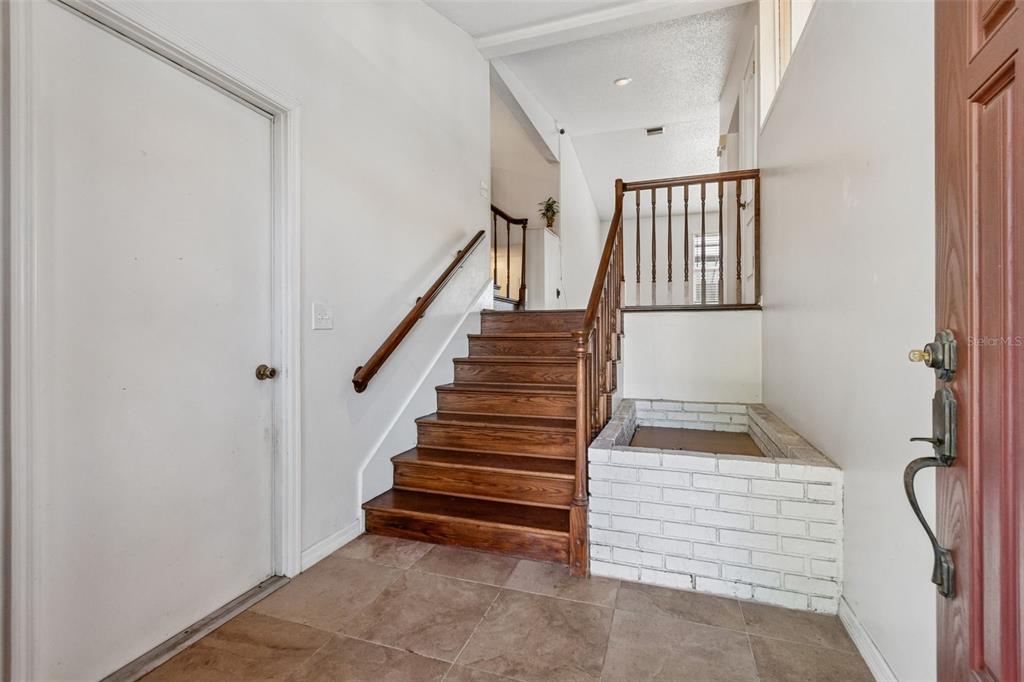 An entryway features a wooden staircase, a white brick planter, and tile flooring — 2620 GIANT PLACE, SEFFNER, FL