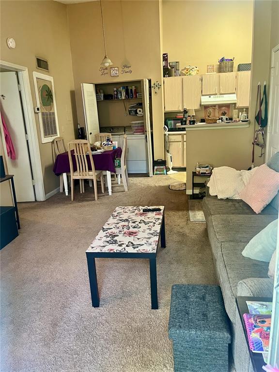 A living room with a floral coffee table, a gray sofa, and an adjacent dining area — 709 SECRET HARBOR LANE UNIT 205, LAKE MARY, FL