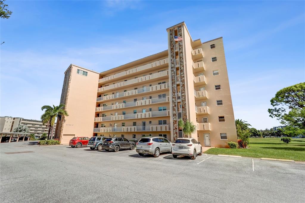 A multi-story beige apartment building with balconies and a parking lot in front — 4040 IRONWOOD CIRCLE UNIT 406F, BRADENTON, FL