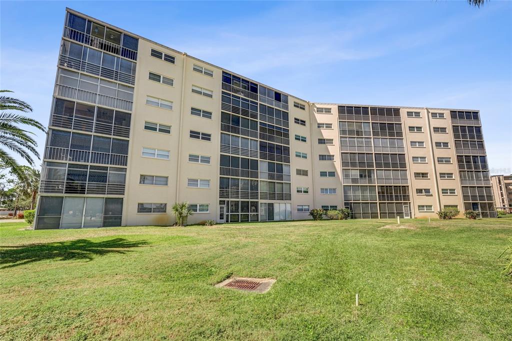A multi-story apartment building with screened balconies sits behind a large, grassy lawn — 4040 IRONWOOD CIRCLE UNIT 406F, BRADENTON, FL