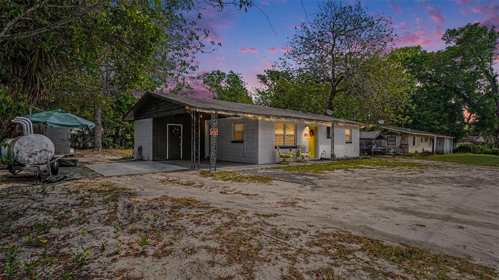 A single-story white brick house with a carport sits on a large sandy lot — 2305 NE 35TH STREET, OCALA, FL