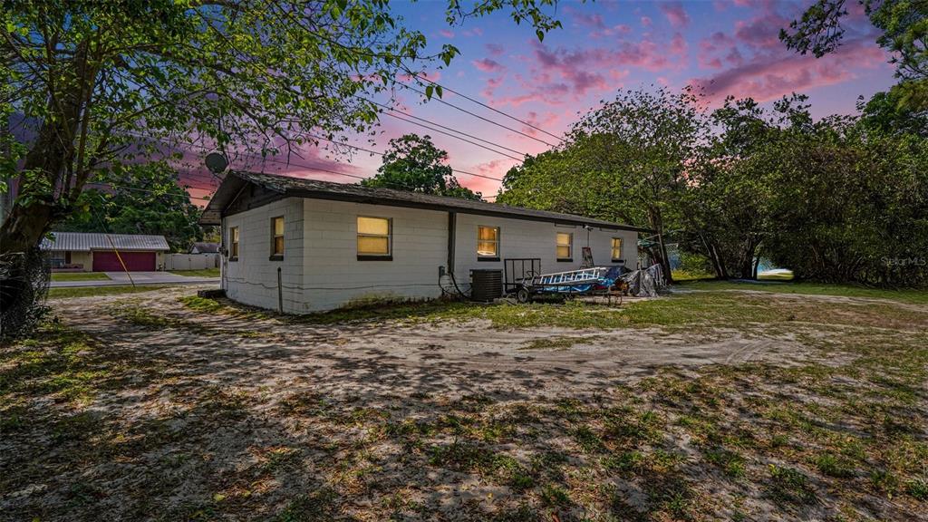 A white concrete block house exterior with a gravel yard under a sunset sky — 2305 NE 35TH STREET, OCALA, FL