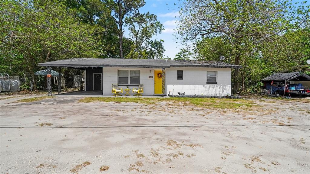 A single-story white house with a yellow front door and a large gravel driveway — 2305 NE 35TH STREET, OCALA, FL