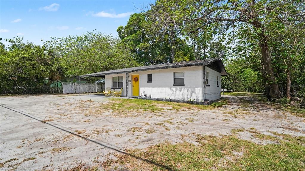 A white concrete block house with a yellow front door and a covered carport — 2305 NE 35TH STREET, OCALA, FL