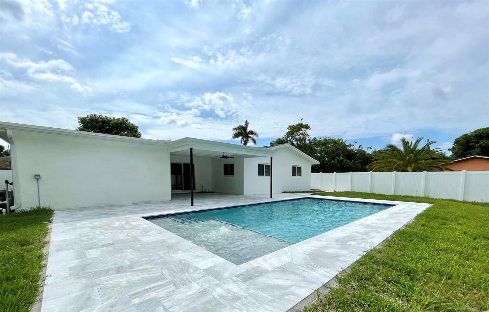 A white house with a covered patio overlooks a rectangular swimming pool and lawn — 1101 NW 5th Avenue, Boca Raton FL 33432, BOCA RATON, FL