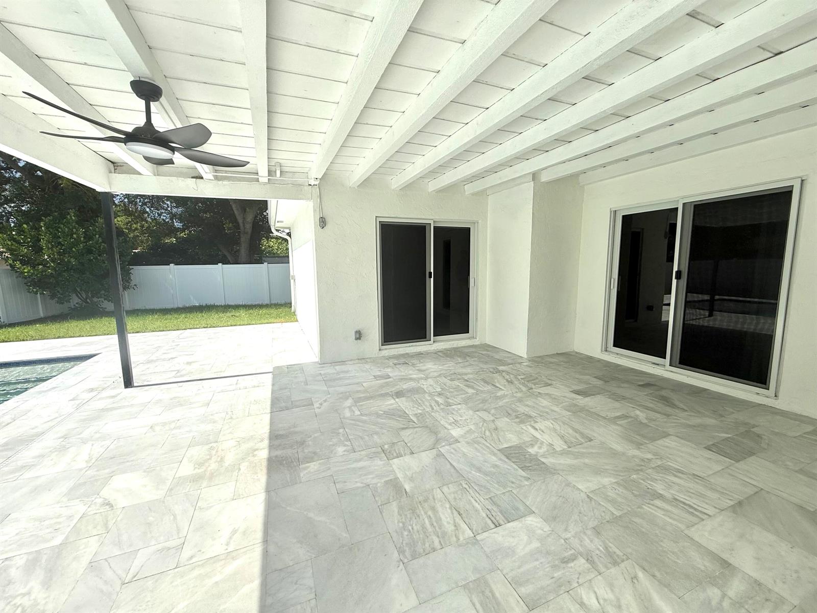 A covered patio features light-colored stone tile flooring, a ceiling fan, and two sliding doors — 1101 NW 5th Avenue, Boca Raton FL 33432, BOCA RATON, FL