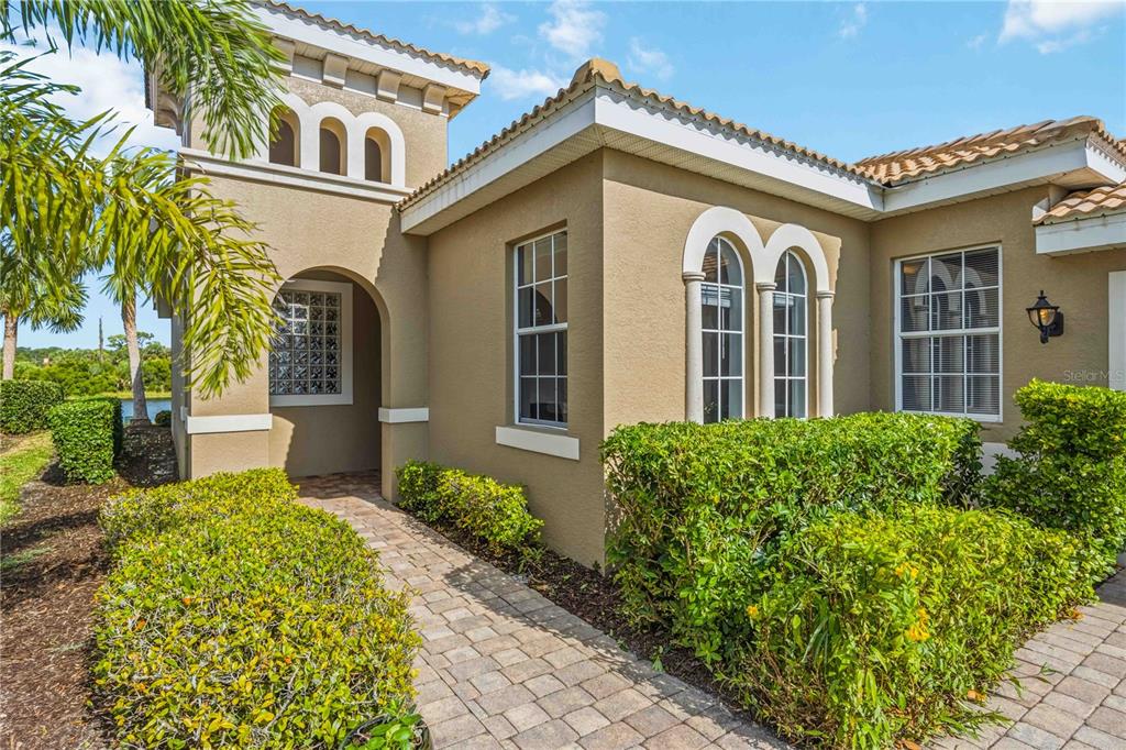 A tan stucco house exterior features a stone walkway, arched entryway, and arched windows — 170 CIPRIANI WAY, NORTH VENICE, FL