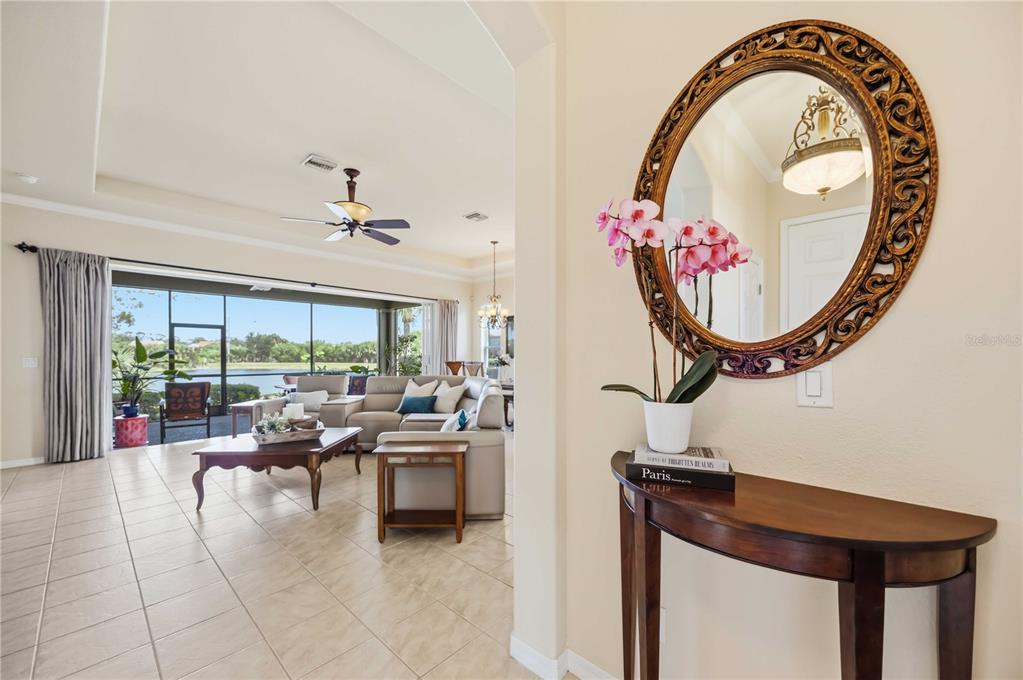 A foyer with a decorative mirror and console table opens into a spacious living room — 170 CIPRIANI WAY, NORTH VENICE, FL