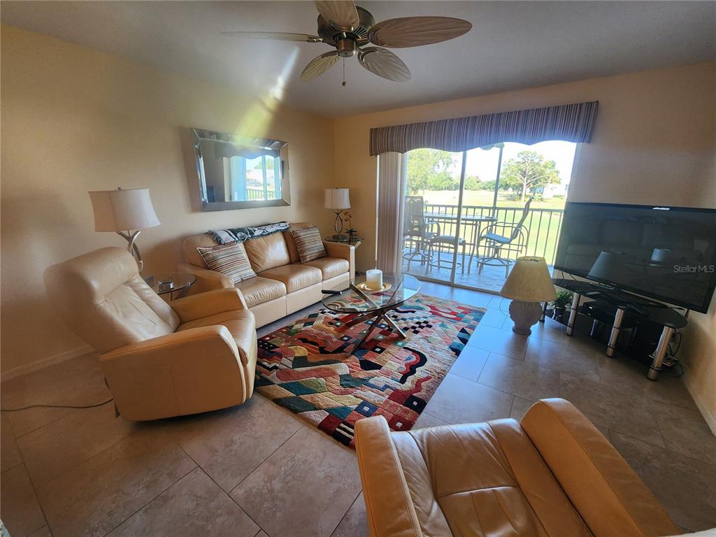 A living room features tile floors, a leather sofa, two recliners, and a sliding glass door — 6507 STONE RIVER ROAD UNIT 205, BRADENTON, FL
