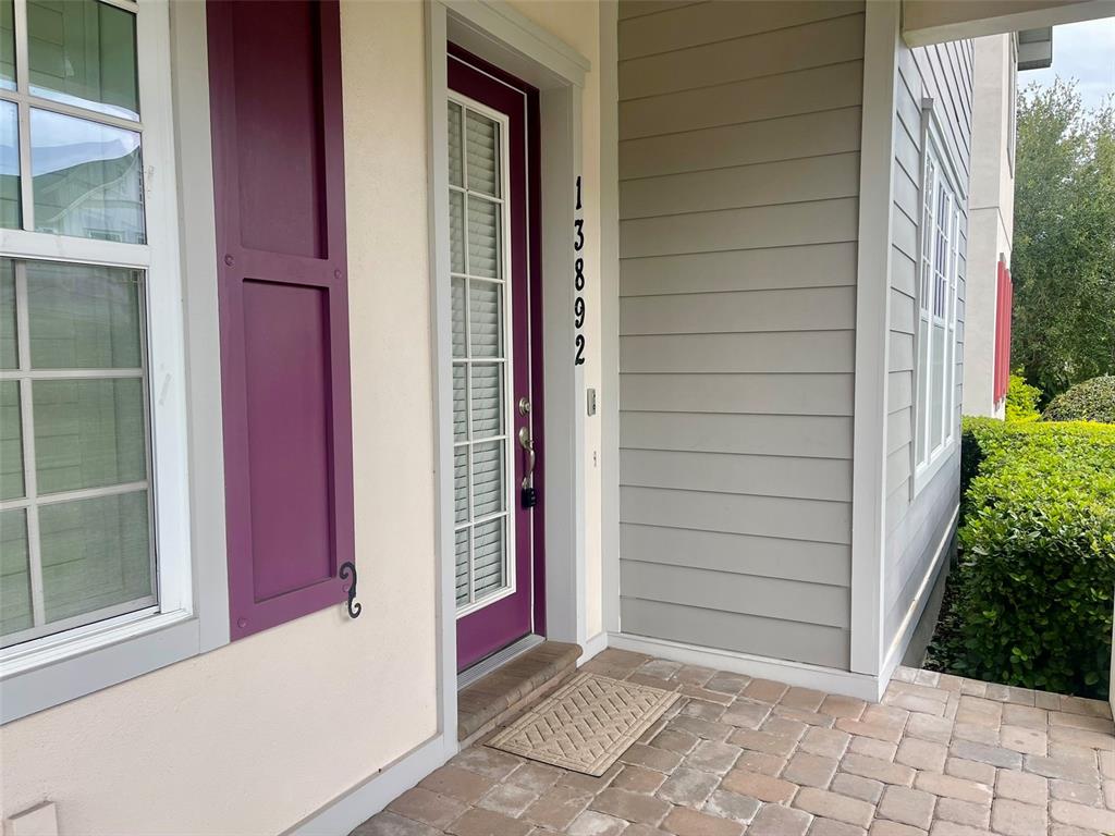 A front porch features a purple door with a glass insert and a brick floor — 13892 HEANEY AVENUE, ORLANDO, FL