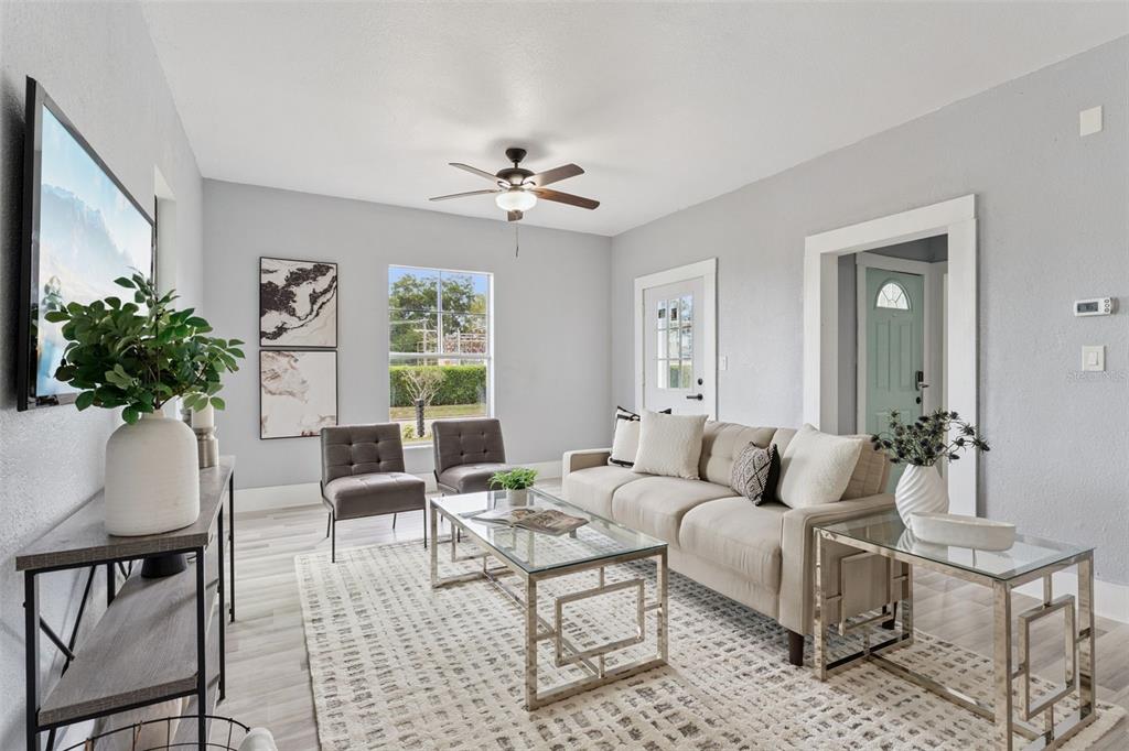 A bright living room features a beige sofa, two gray chairs, and a glass coffee table — 417 W 6TH STREET, SANFORD, FL