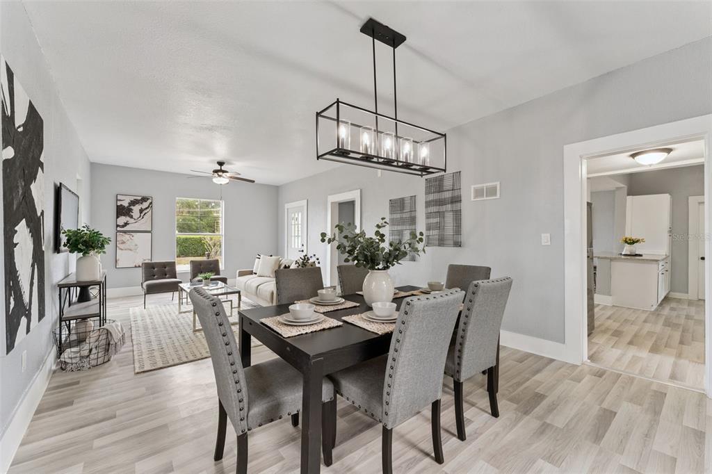 A dining area with a dark table and grey chairs opens into a living room — 417 W 6TH STREET, SANFORD, FL
