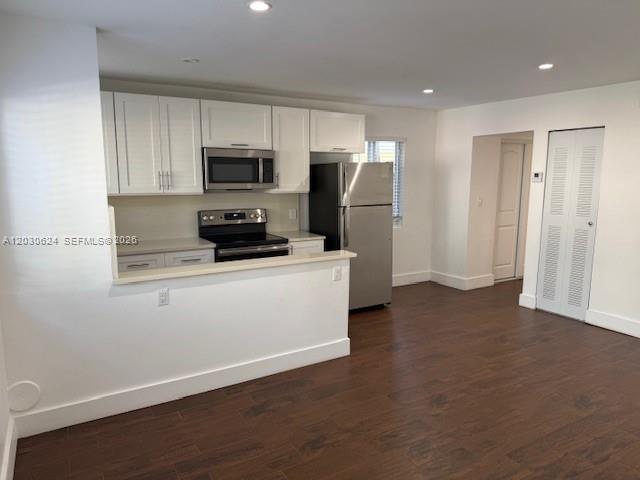 A kitchen features white cabinets, stainless steel appliances, and dark wood-look flooring — 2006 Calais Dr # 1, Miami Beach FL 33141, MIAMI BEACH, FL