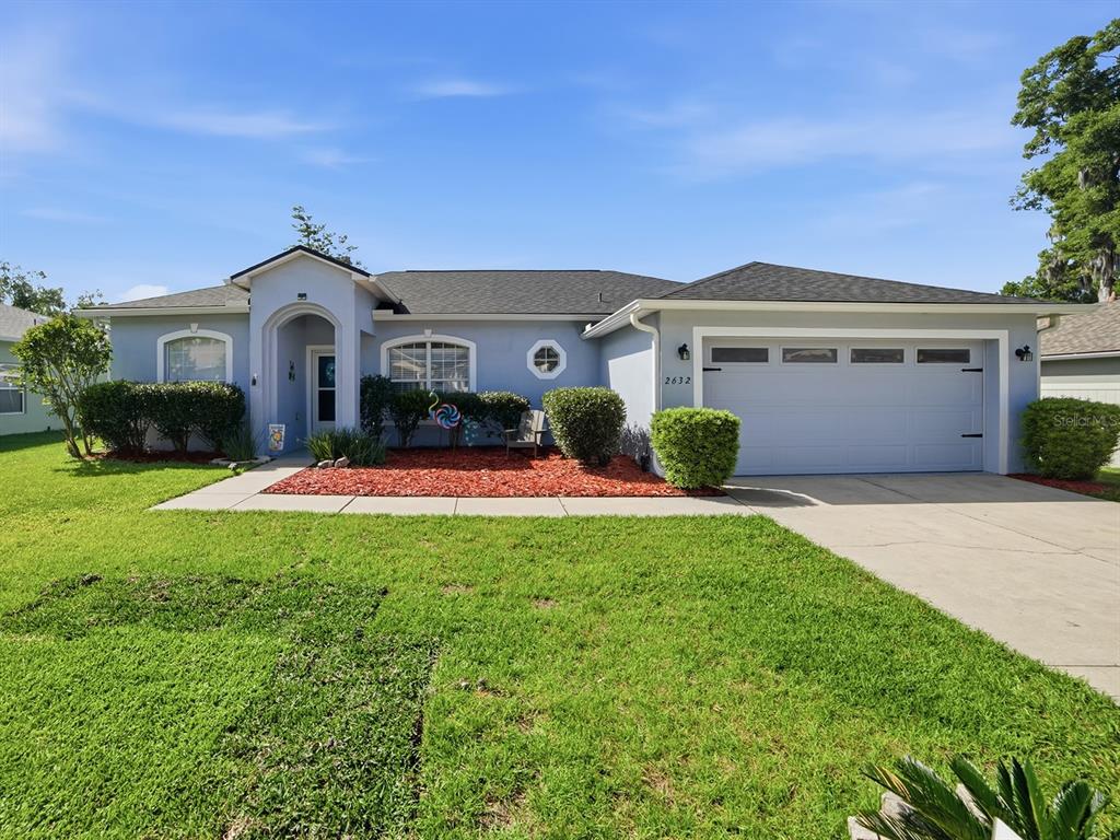 A single-story house with a gray exterior, a two-car garage, and a red mulch garden — 2632 NE 27TH STREET, OCALA, FL