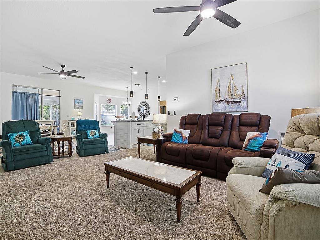 A living room features a brown sofa, several armchairs, a coffee table, and ceiling fans — 2632 NE 27TH STREET, OCALA, FL