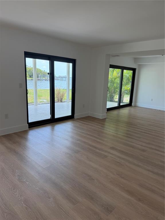 An interior room with light wood-look flooring and two sets of black-framed sliding glass doors — 105 AUGUSTA AVENUE, PALM HARBOR, FL