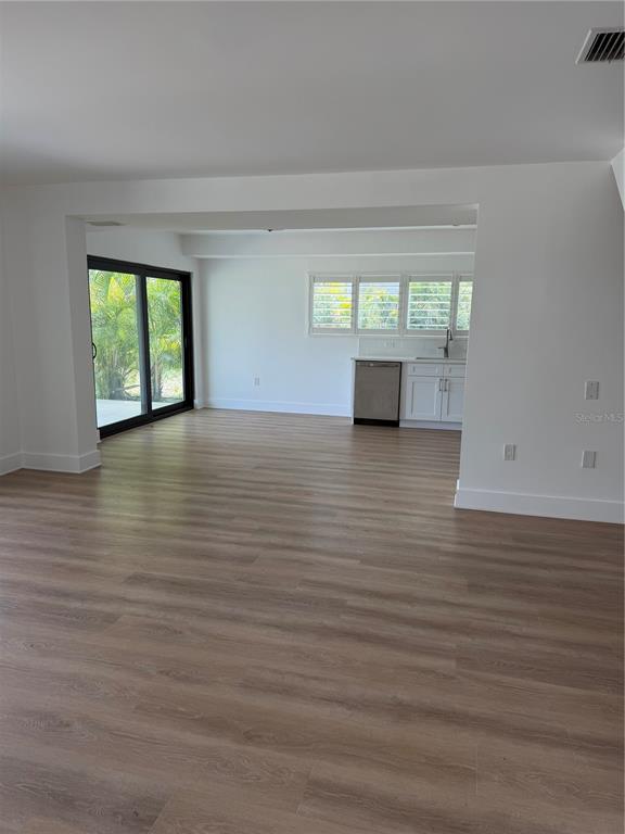 A bright room with light wood-look flooring, a sliding glass door, and a small kitchenette — 105 AUGUSTA AVENUE, PALM HARBOR, FL