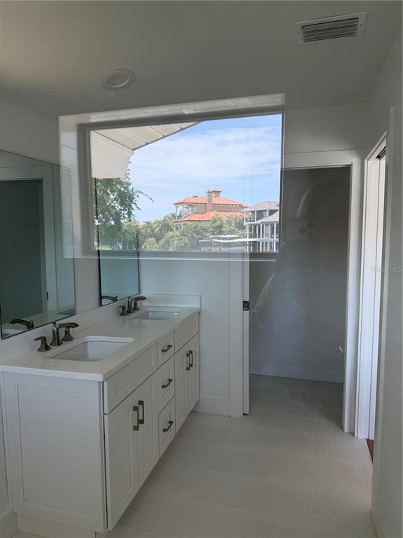 A bathroom features a double vanity with white cabinets, quartz countertops, and a large window — 105 AUGUSTA AVENUE, PALM HARBOR, FL