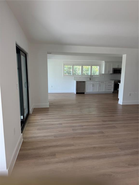 A view of a kitchen with white cabinets and light wood-look flooring — 105 AUGUSTA AVENUE, PALM HARBOR, FL