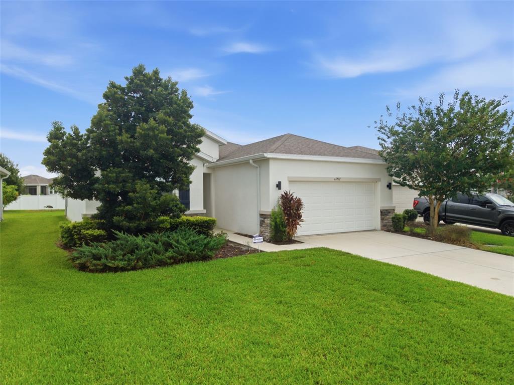 A single-story house with a white stucco exterior, a two-car garage, and a front lawn — 13237 WATERLEAF GARDEN CIRCLE, RIVERVIEW, FL
