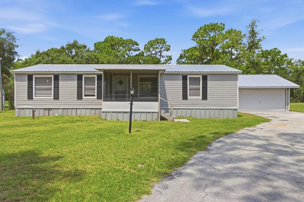 A single-story manufactured home with light gray siding, a metal roof, and an attached garage — 7230 S SONATA AVENUE, HOMOSASSA, FL