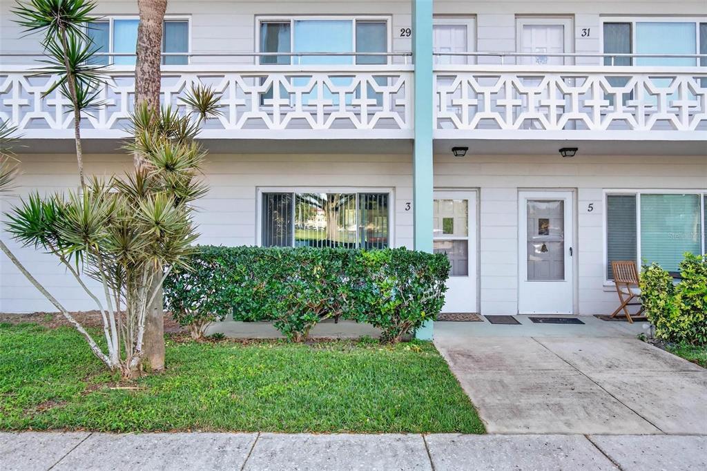 The exterior of a two-story apartment building features white siding, balconies, and numbered unit doors — 2455 FINLANDIA LANE UNIT 3, CLEARWATER, FL