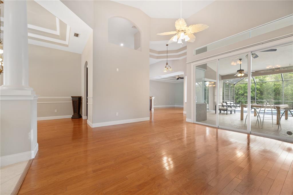 A spacious living area with hardwood floors, a vaulted ceiling, and sliding glass doors — 15 OLD OAK DRIVE N, PALM COAST, FL