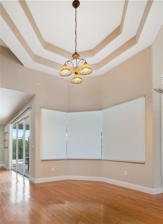 A dining area features hardwood floors, a tray ceiling, a chandelier, and large bay windows — 15 OLD OAK DRIVE N, PALM COAST, FL