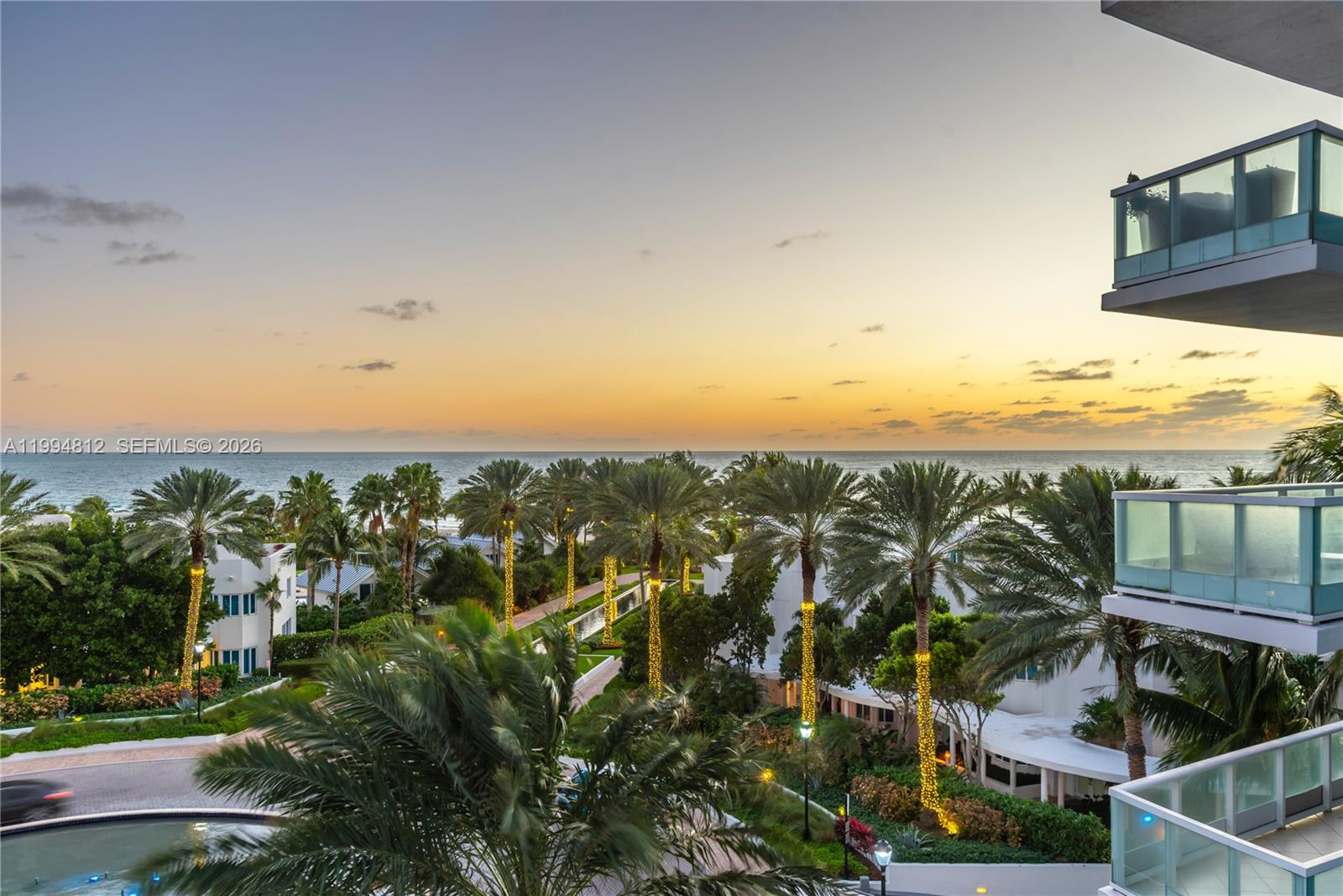 An elevated view of a tropical resort courtyard with palm trees at sunset — 100 S Pointe Dr # 610, Miami Beach FL 33139, MIAMI BEACH, FL