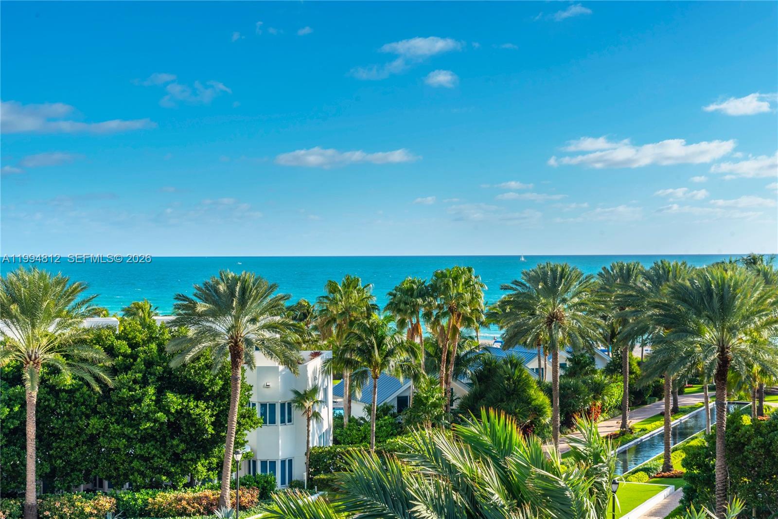 An elevated view shows palm trees, a white building, and a swimming pool near the ocean — 100 S Pointe Dr # 610, Miami Beach FL 33139, MIAMI BEACH, FL