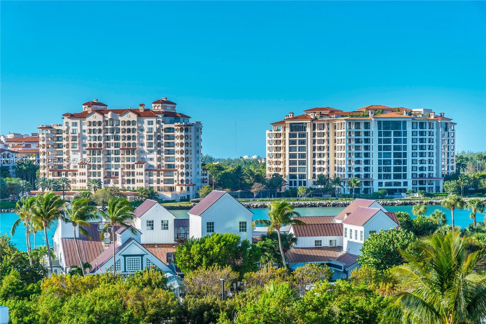 An exterior view shows two large apartment buildings overlooking a canal and smaller white houses — 100 S Pointe Dr # 610, Miami Beach FL 33139, MIAMI BEACH, FL