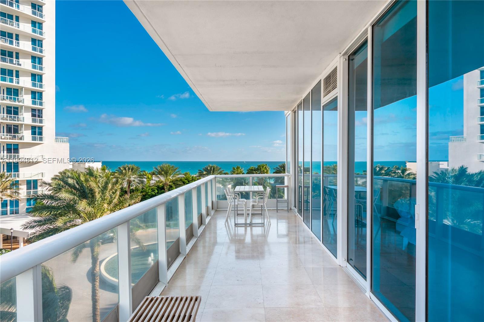 A balcony with tile flooring, a glass railing, and a small table overlooks the ocean — 100 S Pointe Dr # 610, Miami Beach FL 33139, MIAMI BEACH, FL