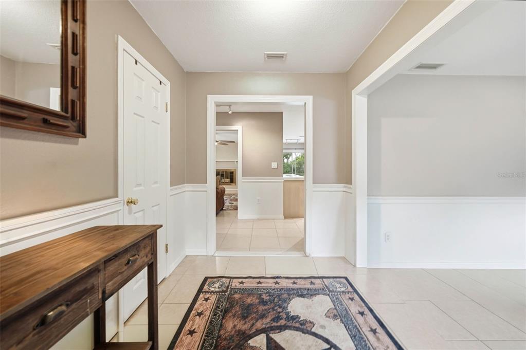 An entryway with tile flooring, a wooden console table, and a view into another room — 112 E GARDENIA STREET, HOWEY IN THE HILLS, FL
