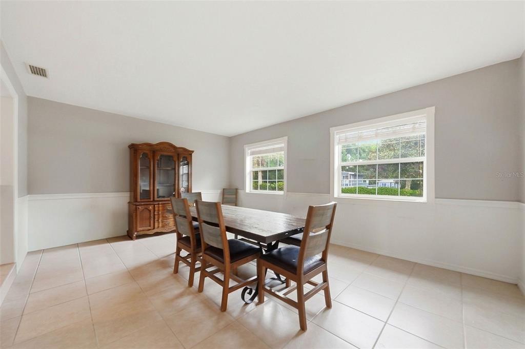 A dining room with tile floors, wainscoting, a wooden table with chairs, and a hutch — 112 E GARDENIA STREET, HOWEY IN THE HILLS, FL