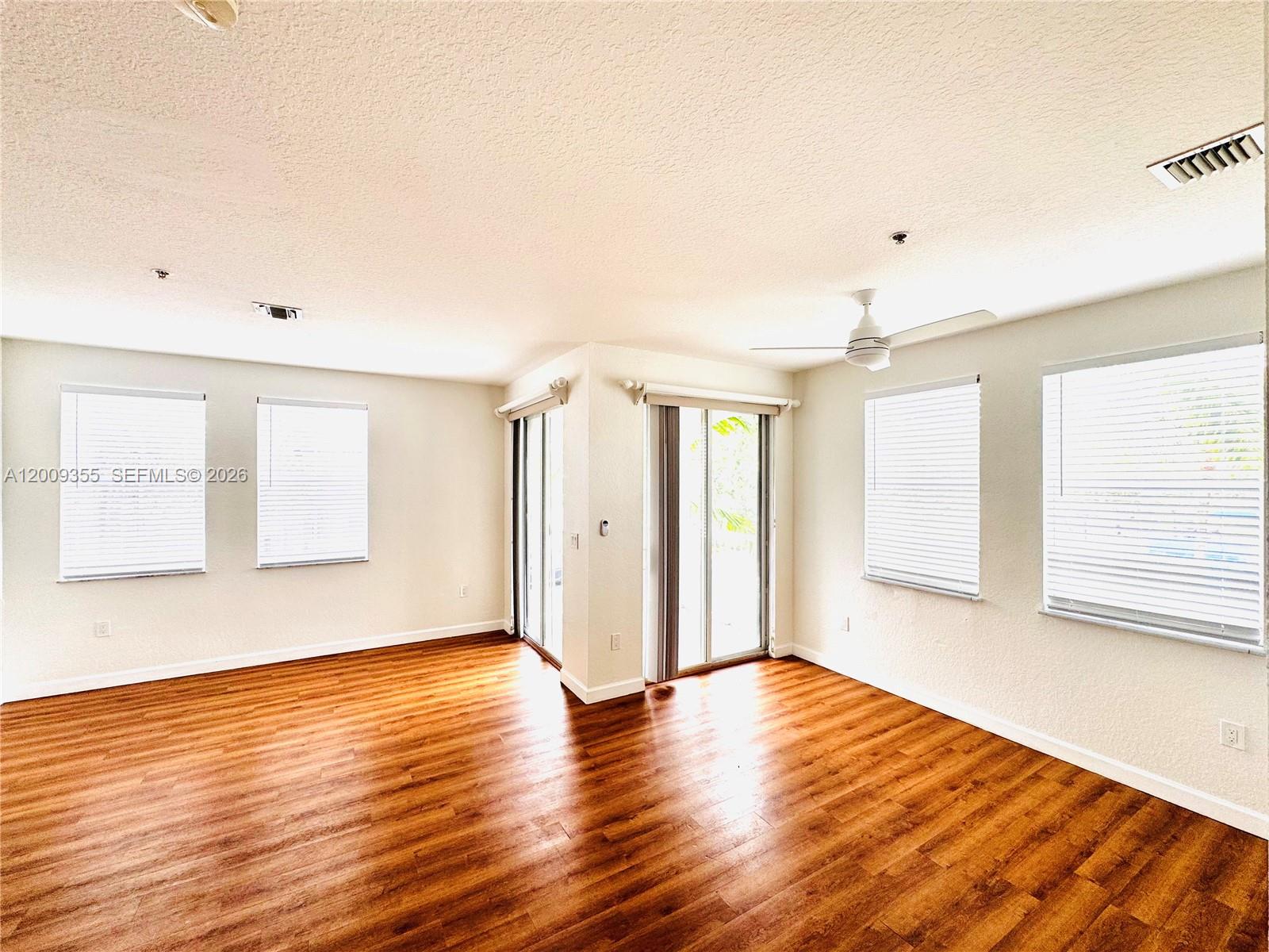 An empty room features wood-look flooring, white walls, a ceiling fan, and sliding glass doors — 4435 SW 160th Ave # 214, Miramar FL 33027, MIRAMAR, FL