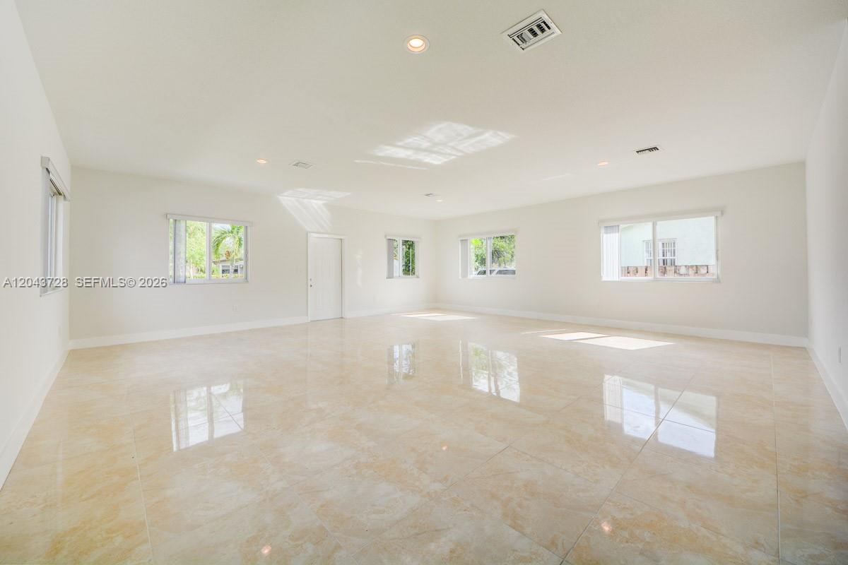 A large, empty room features white walls, recessed lighting, and polished light-colored tile flooring — 312 Phippen Waiters Rd, Dania Beach FL 33004, DANIA BEACH, FL