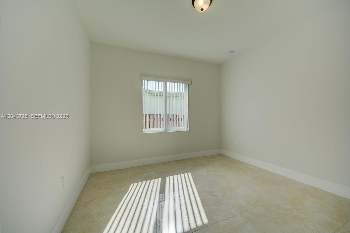 An empty room features light-colored tile flooring, white walls, and a single window with blinds — 312 Phippen Waiters Rd, Dania Beach FL 33004, DANIA BEACH, FL