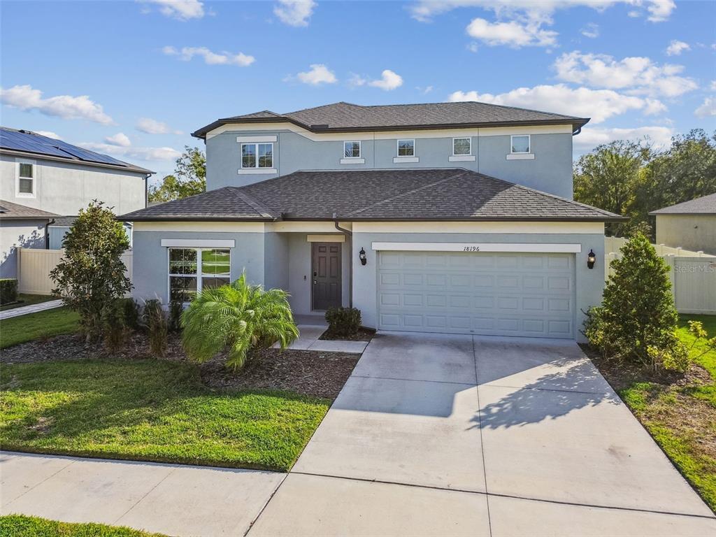 A two-story light blue house features a two-car garage and a front yard with landscaping — 18196 PORFIRIO PLACE, SPRING HILL, FL