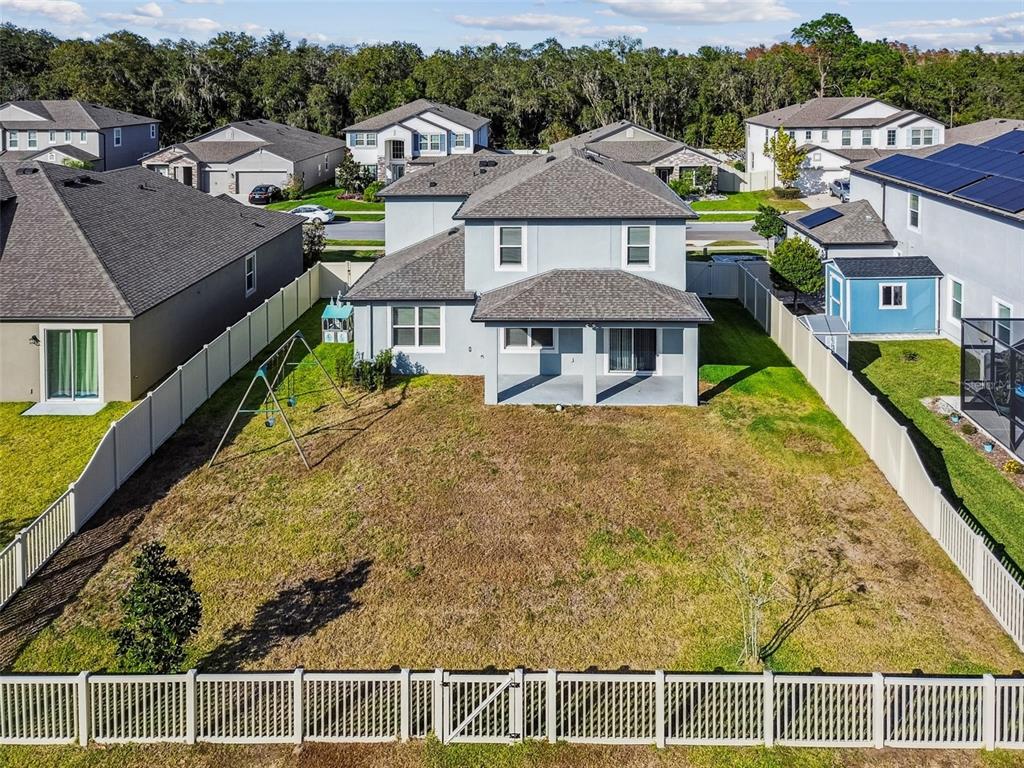 An aerial view shows the backyard of a two-story house with a white vinyl fence — 18196 PORFIRIO PLACE, SPRING HILL, FL