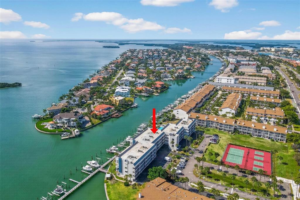 An aerial view shows a multi-story waterfront condominium building with a marina and tennis courts — 363 PINELLAS BAYWAY S UNIT 42, ST PETERSBURG, FL