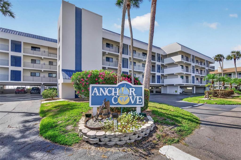 A multi-story apartment building stands behind a sign for Anchor Cove with palm trees — 363 PINELLAS BAYWAY S UNIT 42, ST PETERSBURG, FL