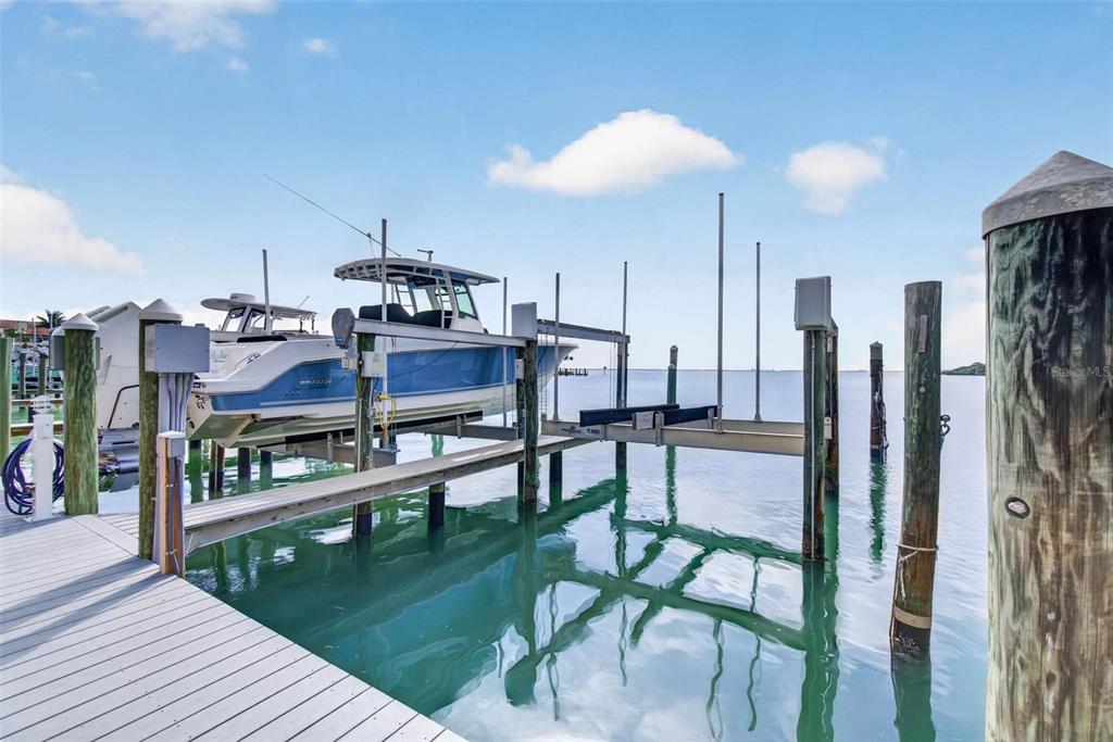 A boat is lifted on a mechanical dock system over calm water under a blue sky — 363 PINELLAS BAYWAY S UNIT 42, ST PETERSBURG, FL